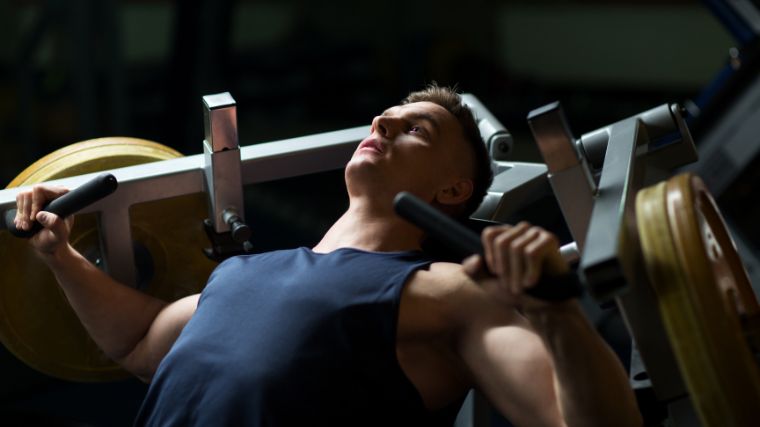 A bodybuilder using a chest press machine in the gym. 