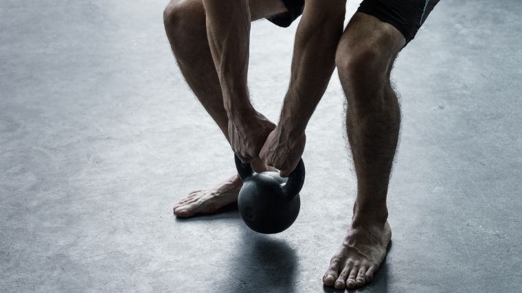 Deadlifting a kettlebell while barefoot.