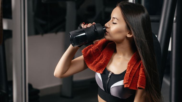 A gymgoer drinking from a water bottle.