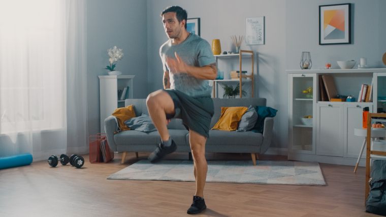 A person doing high knees at home for cardio.