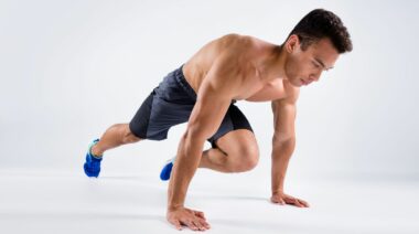 A shirtless athlete doing mountain climbers.