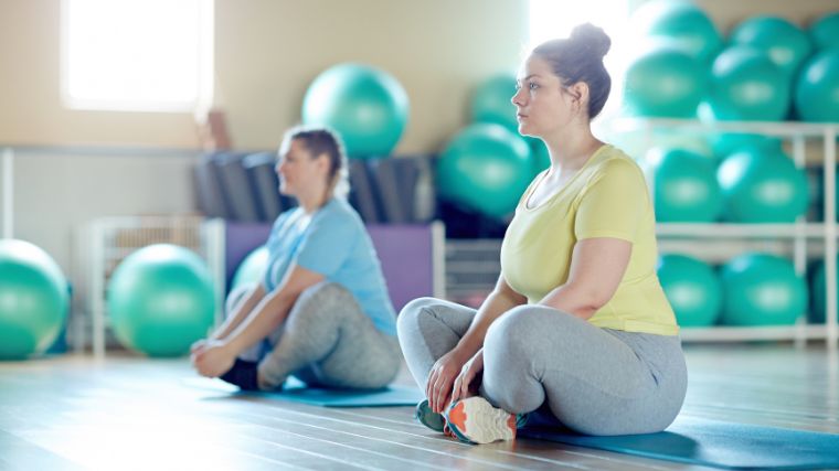 Two people sitting with crossed legs on mats and getting ready for the next exercise.