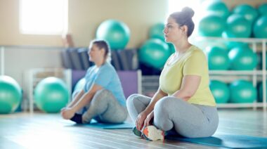 Two people sitting with crossed legs on mats and getting ready for the next exercise.