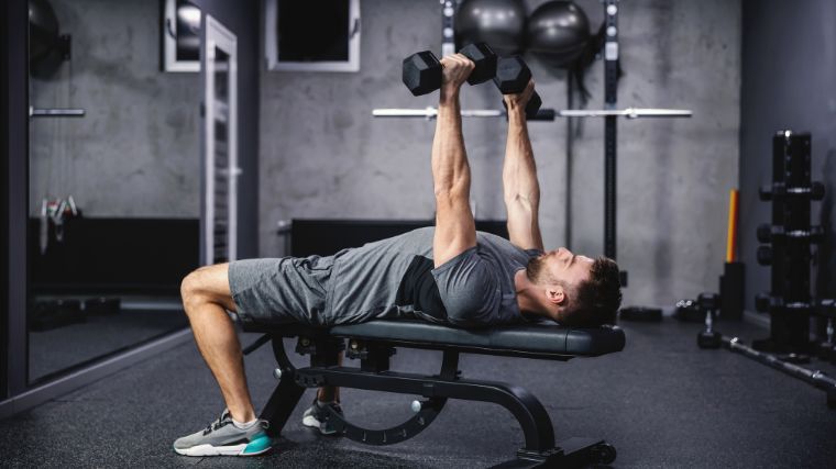 A gymgoer training with dumbbells on the bench.