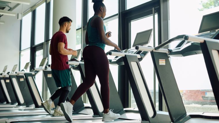 A couple of people on treadmills in the gym.