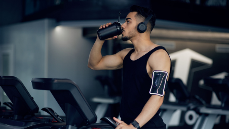 Man drinks supplement while exercising on treadmill.