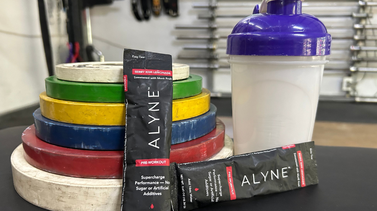 Product tester trying Alyne pre-workout packet in gym.
