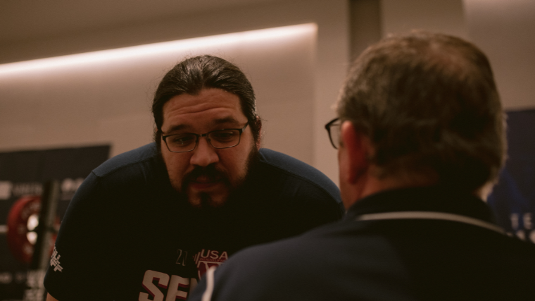 Weightlifter Caine Wilkes consults a coach during a workout.