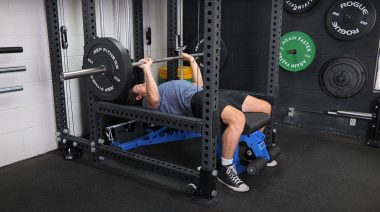 A person performing the barbell bench press exercise.