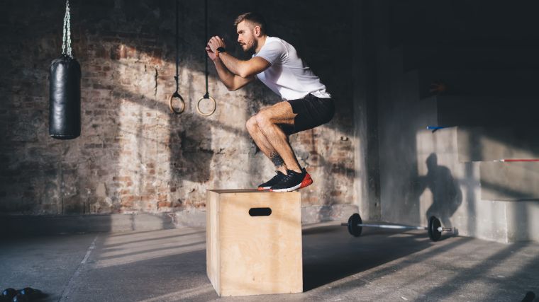 A muscular person doing box jumps.