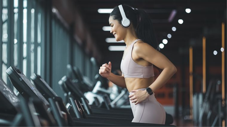 A person running on the treadmill while listening to music using a headset.