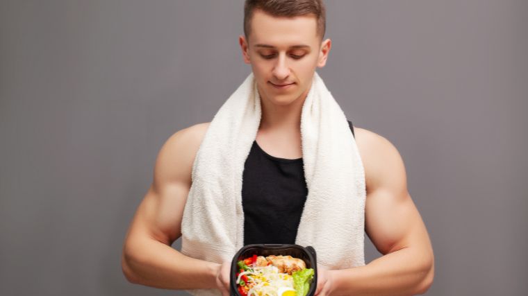 A muscular person holding a container of food with a ketogenic meal. 