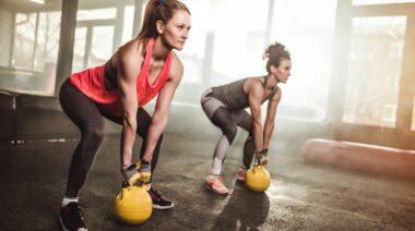 Two people doing kettlebell glute workouts in the gym.