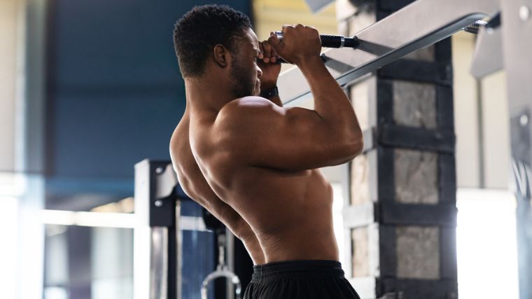 A muscular person doing pull-ups with a neutral grip.