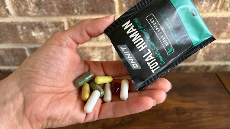 A person holds a packet of Onnit Total Human along with the multivitamins themselves.