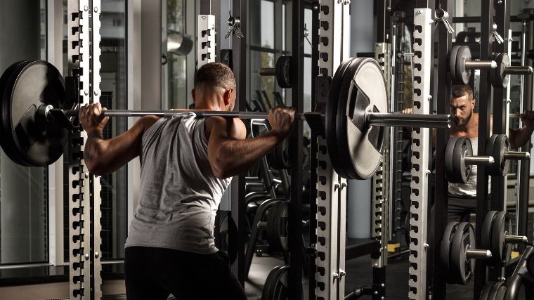 A bodybuilder using a power rack.