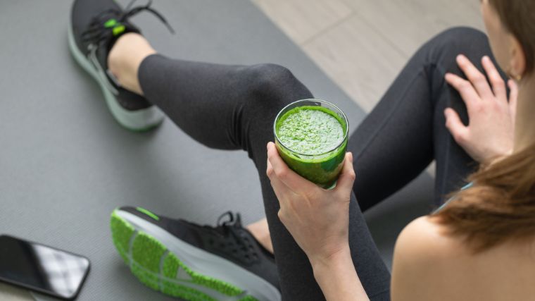 A gym goer with a glass of green pre-workout.