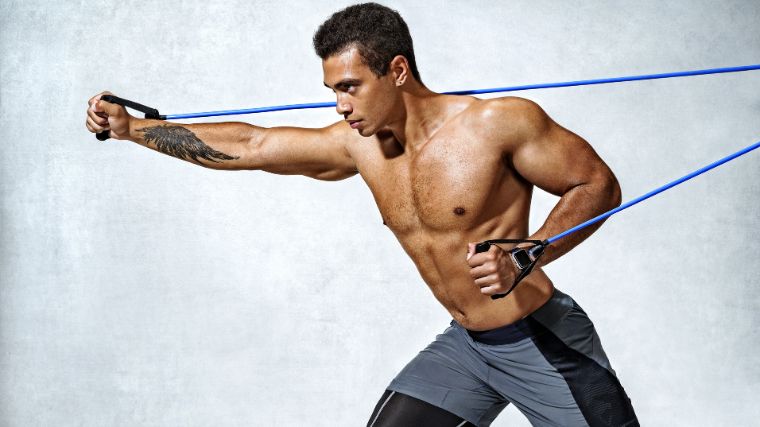 A shirtless athlete using a resistance band to do upper body workouts.