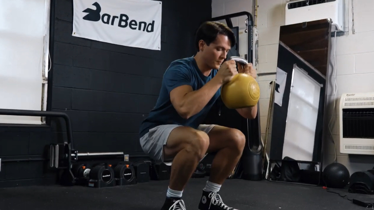 A fit person performing the goblet squat exercise.