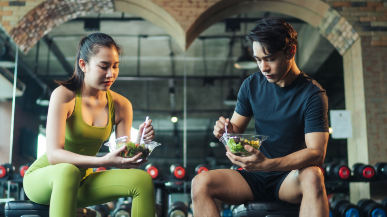 Two people eating in the gym.