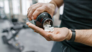 A man taking vitamins at the gym.