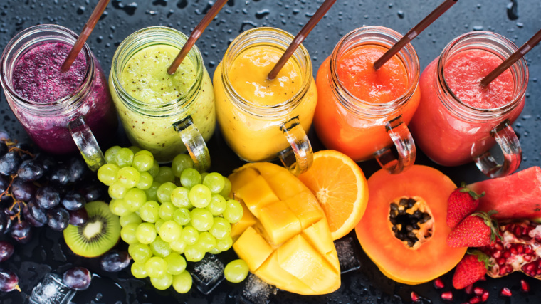 Five glasses of protein shakes with different fruits.