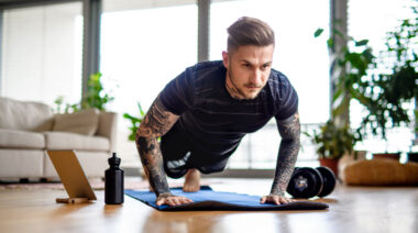 A person with full arm tattoos doing push-ups.