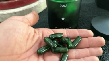 A person holding a handful of Seed Daily Synbiotic capsules.