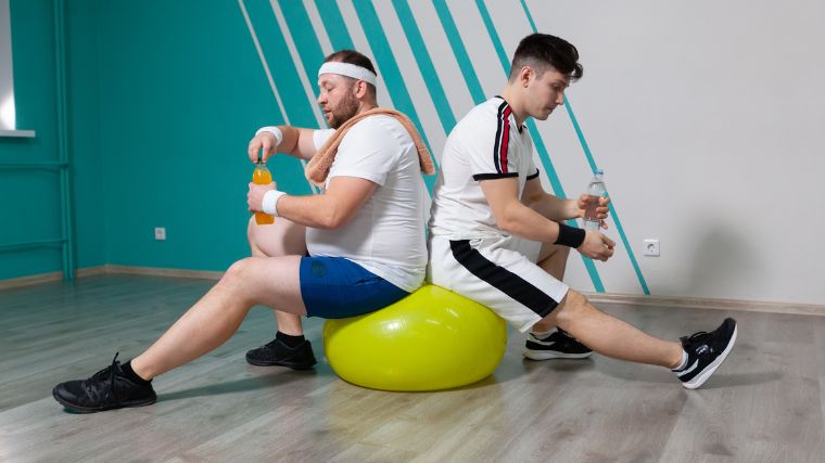 Two people sitting on a stability ball.