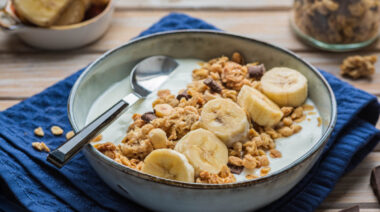 A bowl of oats, cereal and sliced bananas.