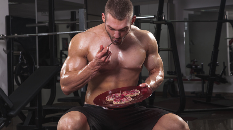 A muscular  person  eating in the gym.