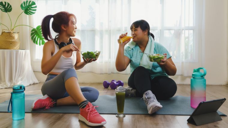 A couple of people eating healthy while on a yoga mat.