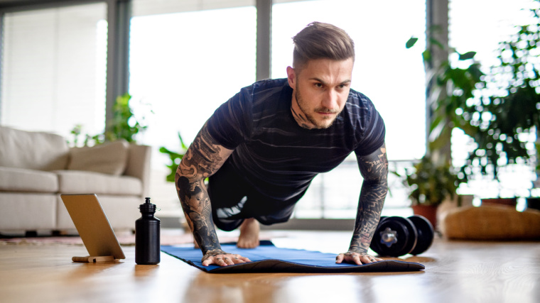 A person with full arm tattoos doing push-ups.
