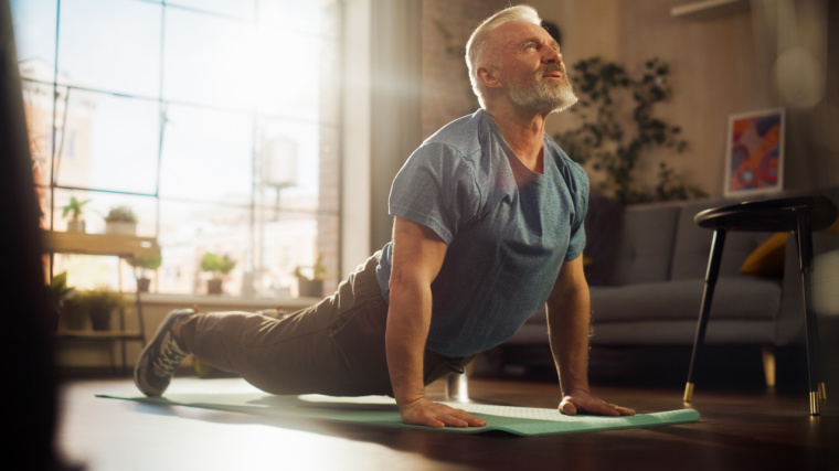 A senior person stretching at home on an exercise mat.