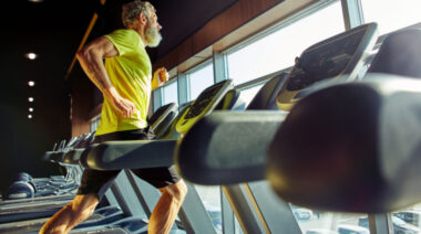 A muscular gymgoer running on a treadmill.