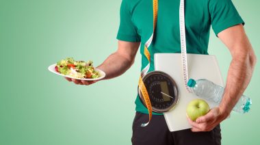 A person carrying a salad plate, measuring tape, meter scale, an apple and a water bottle.