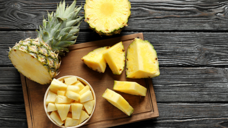Wooden board with fresh sliced pineapple on the table.