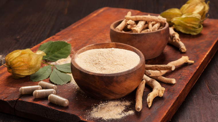 Ashwagandha tablets, roots and powders on a wooden board.