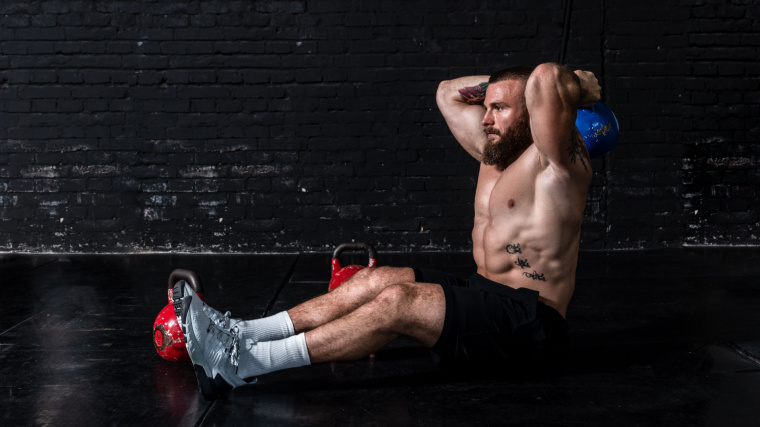 A fit person doing weight training with a kettlebell in the gym.