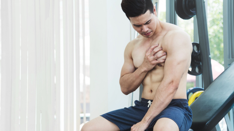 An athlete having pain on his chest while working out at the gym. 