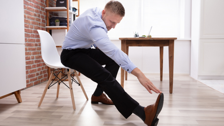 A person doing leg stretching sitting on a chair at his workplace