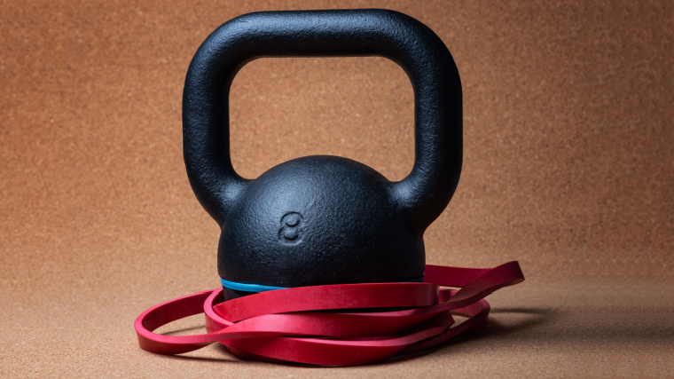 A kettlebell with a red resistance band around it.