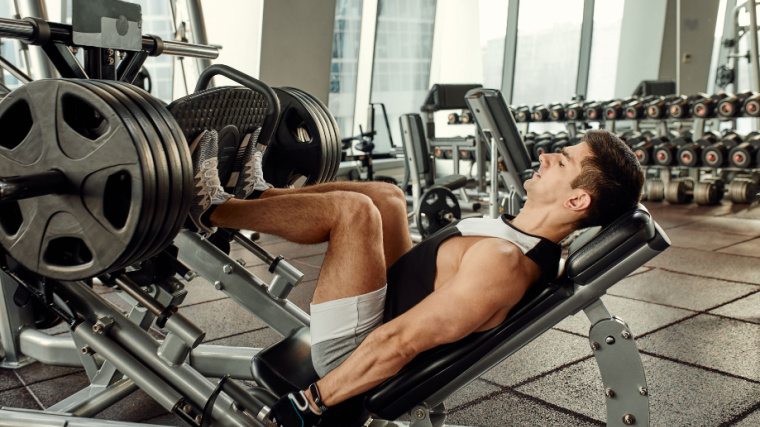 A person doing workout on a leg press machine inside the gym.