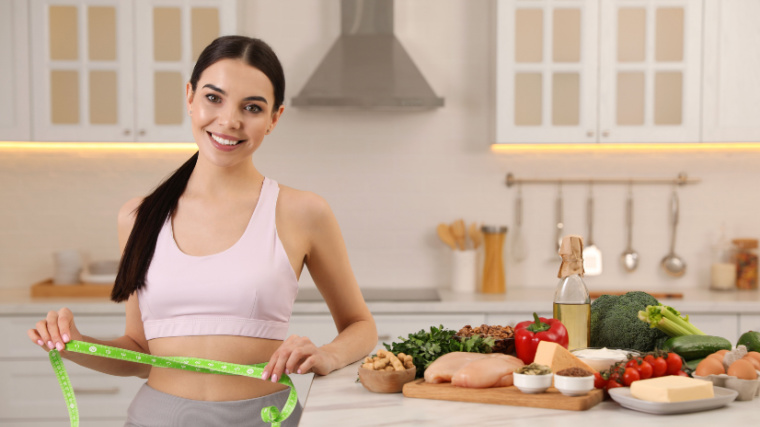 A person measuring her waist size with foods rich in protein in her kitchen at the back