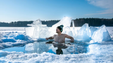 A person taking an ice bath in a frozen area during winter