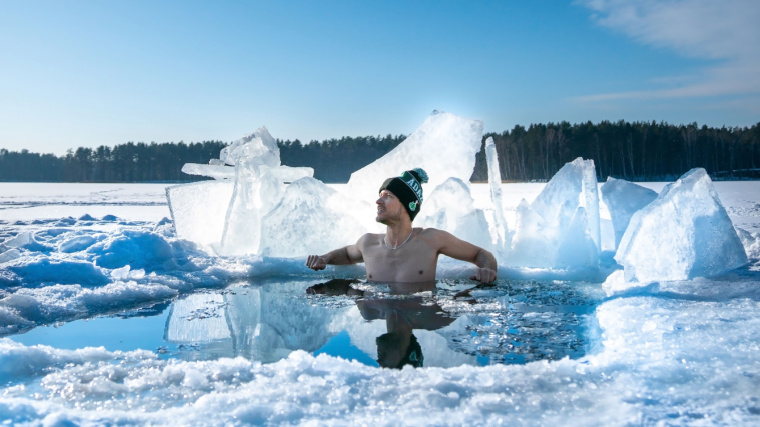 A person taking an ice bath in a frozen area during winter.