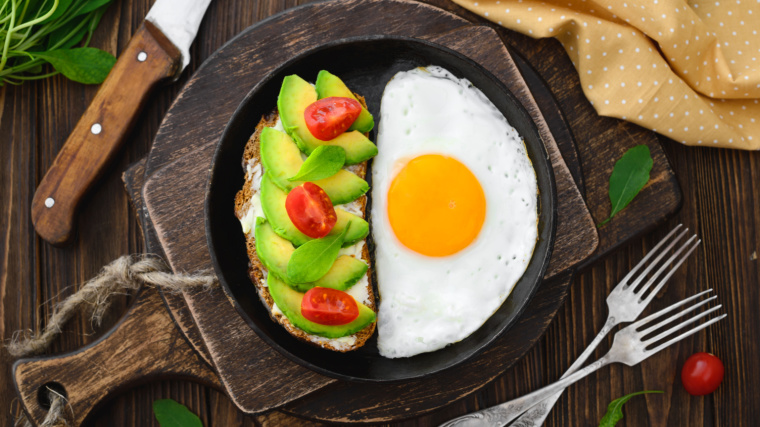 Fried egg in pan and an avocado slices for sandwich top