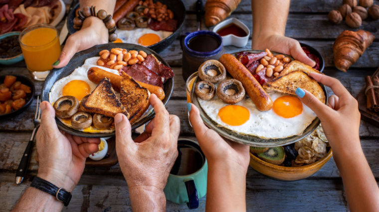 Plates filled with protein rich food for breakfast like egga, bacon, sausage, and others.