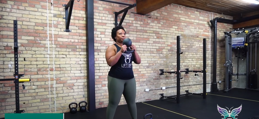 A fit person doing the kettlebell halo exercise in the gym.