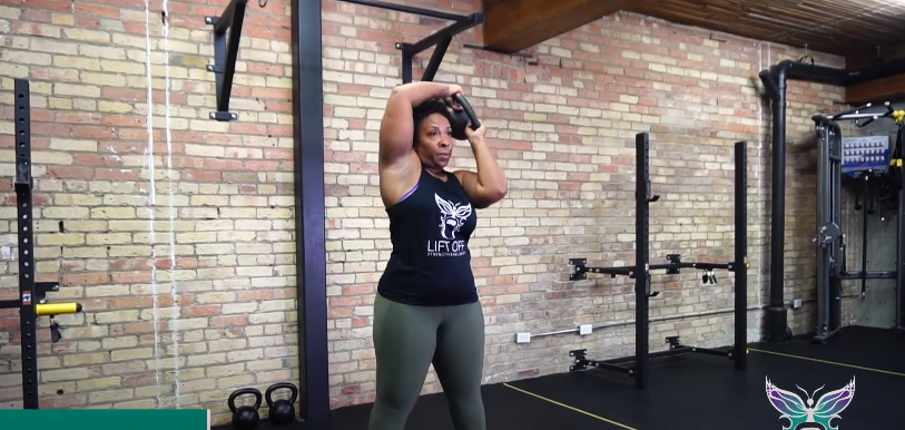 A fit person doing the kettlebell halo exercise in the gym.